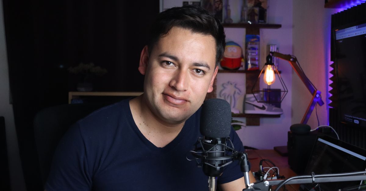 Podcaster in his home studio with microphone and laptop, creating digital content.